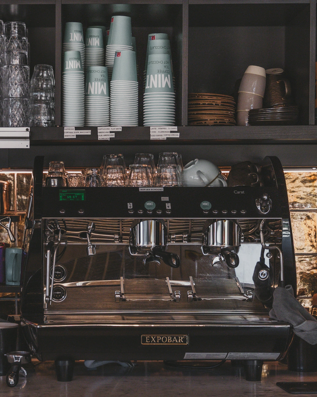 Espresso machine with stacked cups on shelves above